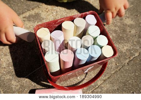 Children's hands and colorful chalk on a playground