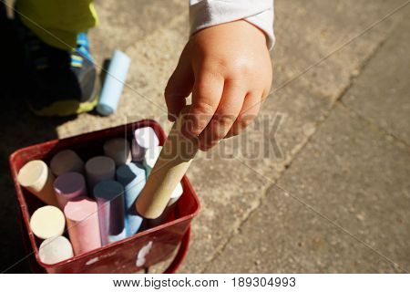Children's hands and colorful chalk on a playground
