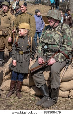 Gatchina, Russia - May 7, 2017: Historical reconstruction of the battles of World War II. German soldiers and the girl in the form of the Soviet army rest and laugh after reconstruction.