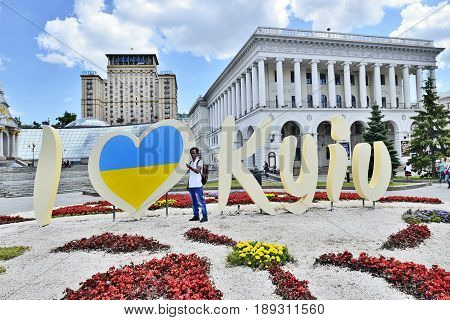 KYIV UKRAINE - CIRCA MAY 2017: Celebration 1535-th Day of Kyiv. Guest African youth stands near stylized banner I LOVE KYIV for image taking