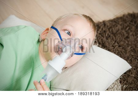 Boy making inhalation with nebulizer at home. child asthma inhaler inhalation nebulizer steam sick cough concept