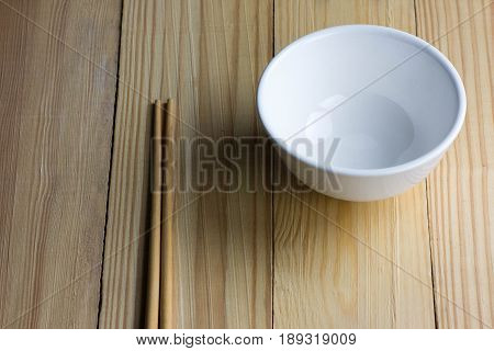 ceramic white bowl and chopsticks on the wooden table