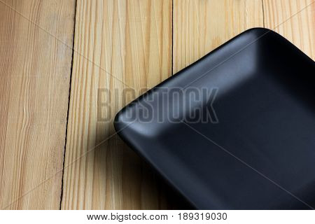 An elegant black plate on a wooden table.
