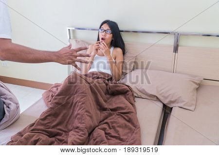 Beautiful young woman wearing glasses sitting on a bed shocked with aggressor the bedroom.