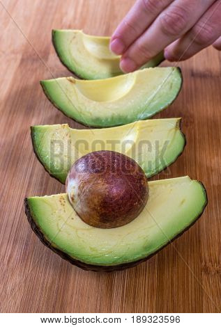 avocado pieces on cutting board with hand in frame