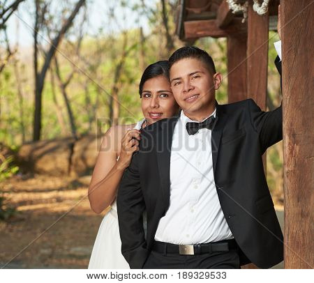Smiling bride and groom stand outside inpark background