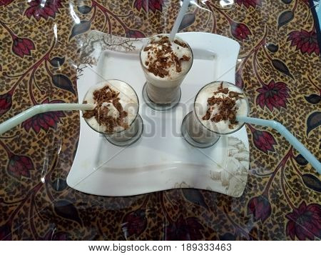 Cold coffee drink frappe with Vanilla ice cream and caramel syrup ,straws and grains of coffee with chocalate chips