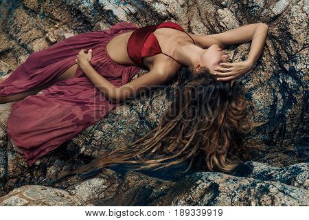beautiful young woman in red dress laying dowm in water