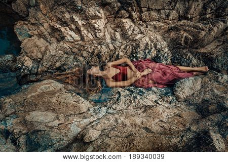 beautiful young woman in red dress laying dowm in water