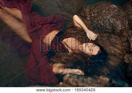 beautiful young woman in red dress laying dowm in water