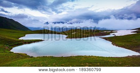 High mountain lake rocky mountains and fog.