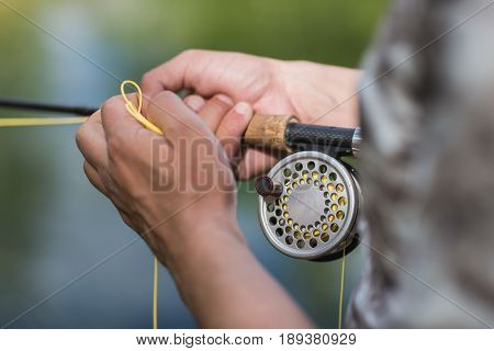 fly fisherman casting his rod on a river, reel closeup