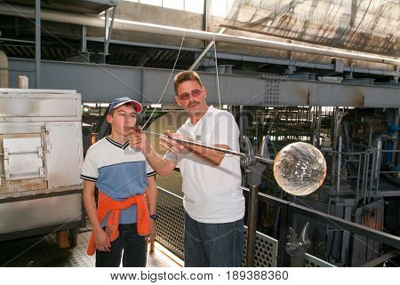 Boy Blowing Into Tube To Make A Glass