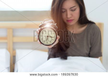 Young sleeping woman and alarm clock in bedroom at home. focus alarm clock