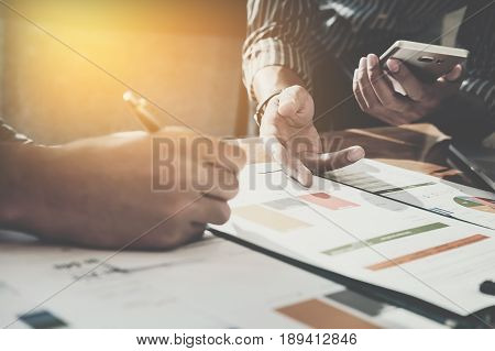 Businessman pointing graph chart with pathner for analyze plans in this month. vintage tone.