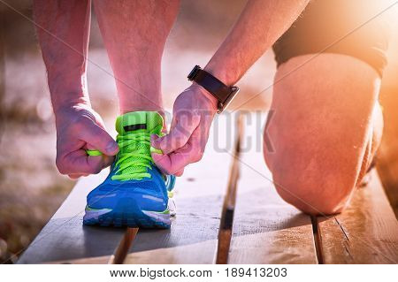 Athlete during training tying shoelaces on sneakers summer.