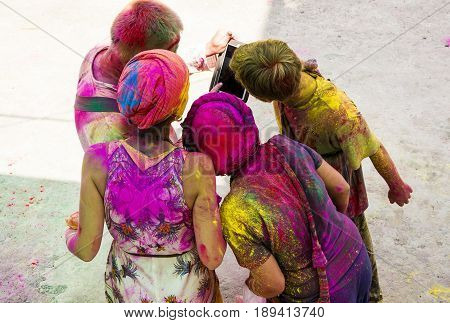 people celebrating holi looking at tablet, Rishkesh, India