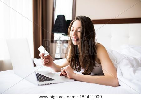 Woman Smiling And Looking In Front Of Her As She Uses Her Credit Card With Her Laptop.