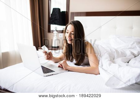 Woman Smiling And Looking In Front Of Her As She Uses Her Credit Card With Her Laptop.