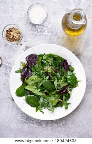 Healthy natural green salad with leaves of spinach arugul on light background. Top view