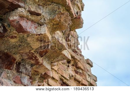 Ancient ruins of the destroyed and broken brick wall of fortress against the background of the sky for the textured background