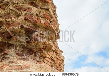 Ancient ruins of the destroyed and broken brick wall of fortress against the background of the sky for the textured background
