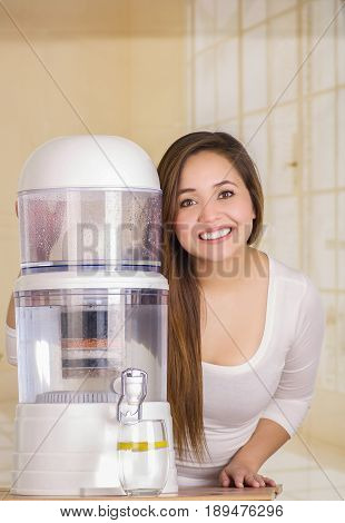 Beautiful woman next to the filter system of water purifier on a kitchen background.