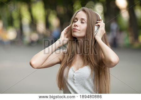 Pretty girl listening music with her headphones in the street