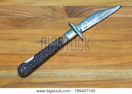 An old and well used jack knife fully open on a wood background