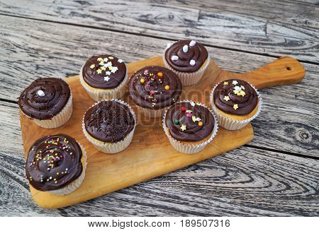 Chocolate Cupcakes. Homemade decorated chocolate cupcakes on natural wood cutting board with rustic background