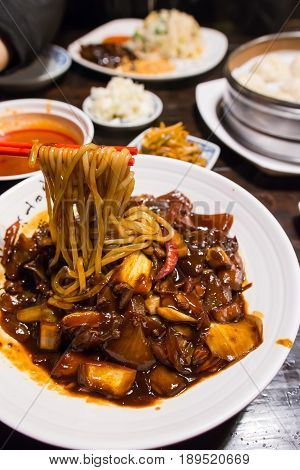 jajangmyeon Korean black noodle with spicy chicken onion and dried chili on a white plate