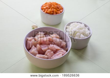 Raw cut chicken fillet with spices and herbs. Small pieces of meat