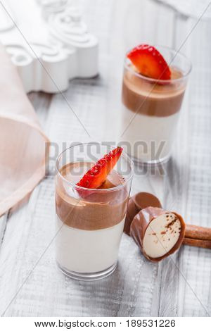 Tasty mousse dessert with chocolate strawberry and praline in a glass on light background close up. Delicious dessert and candy bar. Top view.
