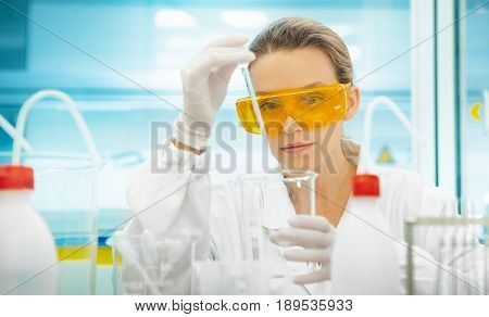 Researcher in lab, woman with pipettes and alb