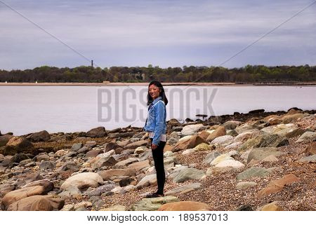 A chinese woman standing on rocks at lowtide at charles island to silver sands state park in Milford connecticut.