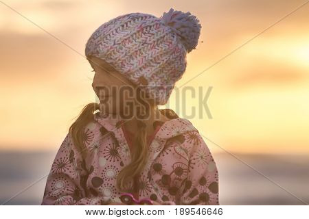 outdoor portrait of young happy smiling child girl in knitted hat on outdoor natural background