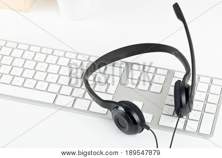 Computer headset with microphone on computer keyboard on white table - communication or helpcenter concept