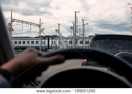 The cars waiting for a train to pass, focus in the background