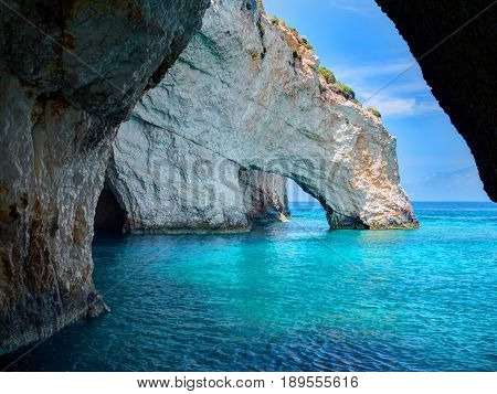 Blue caves rock arces arches of Blue caves from sightseeing boat with tourists in blue water of Ionian Sea inside cave, Island Zakynthos, Greece holidays vacation tour. Trip from Agios Nikolaos port