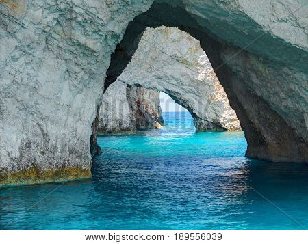 Beautiful view on Blue Caves rock arches from sightseeing boat with tourists in blue water of Ionian Sea inside Blue cave. Stone rocks sea caves. Island Zakynthos Greece holidays vacation trips tours.