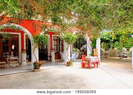 ZAKYNTHOS ISLAND GREECE, MAY 29, 2016: Classical Creece Greek architecture taverna restaurant Dopia House in red white colors table and chairs among grape vine,olive trees. Summer cafe. Greece islands