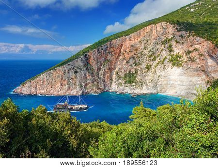 Pirate filibuster boat ship with tourists at Zakynthos blue caves Elation Sparto beach sea bay. Green sand stone rocks at Ionian Sea. Sand beach. Greece islands holidays vacations famous places tours
