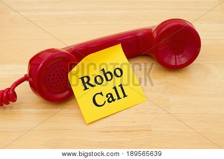 Getting a call from a Robocall Retro red phone handset with a yellow sticky note and text Robocall