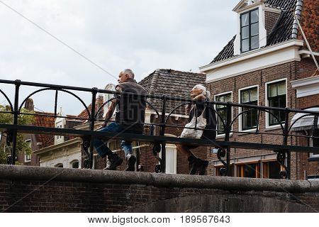 Monnickendam Netherlands - August 08 2016. Unidentified people sitting on bridge over the canal of traditional dutch village of Monnickendam. The town was founded by monks and it is a small fishing village today