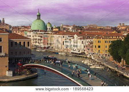 VENICE, ITALY - MAY 23, 2017: People walking on the Constitution Bridge over the Canal Grande of Venice. Beautiful urban landscape with the sunset