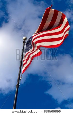 large American flag in the wind with blue sky and clouds