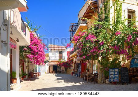 CRETE ISLAND, GREECE, SEP 06, 2012: View on Panormo small city street with bakery restaurant cafe red flowers small hotel for tourists guests Greece islands holidays vacations famous sightseeing tours