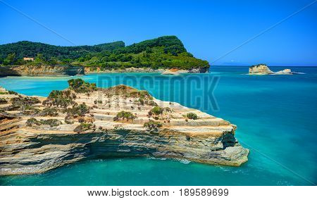 Beautiful view on Corfu island green hills mountains and sand seamy rocks and swimming people in the Ionian blue sea. Sand hill rocks. Greece holidays vacation tourist tour. Sightseeing view point