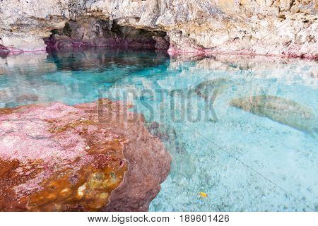 Calm turquoise colored water in coral rock pool in limestone cave at Avaiki on coast of Niue.