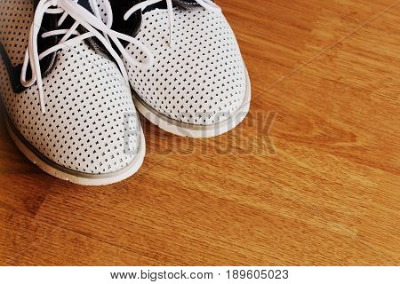 Pair of swhite shoes on wooden background .